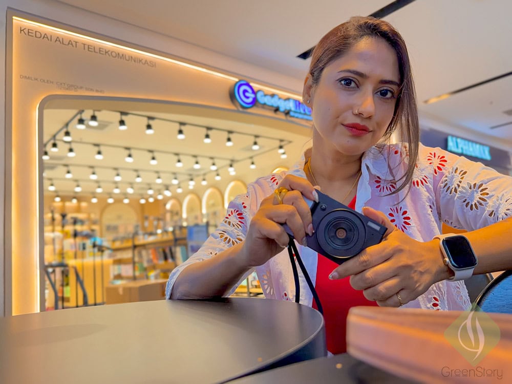 Woman with lumos evoke digital camera at shopping mall, capturing moments.