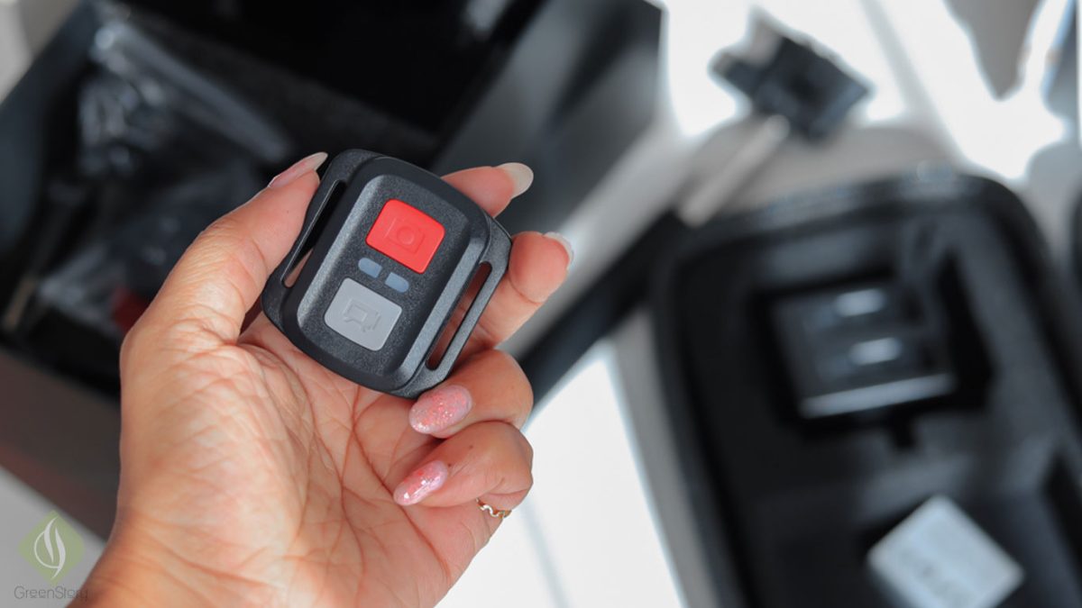 Close-up of a person holding a remote control for the LUMOS DOMINATE action camera.
