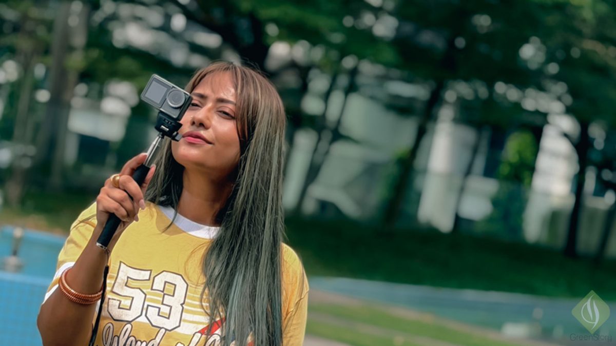 Young woman holding lumos action camera action camera on a selfie stick outdoors.